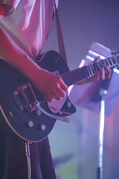 Close-up of a student playing electric guitar on stage