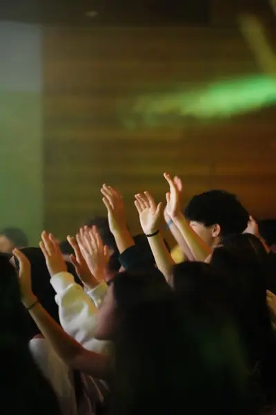 Hands raised in worship under green light
